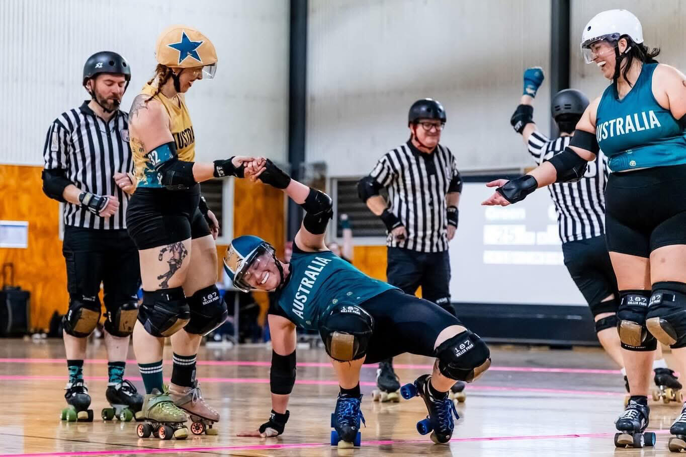 Lauren is wearing a rainbow striped t shirt and holding flyers while smiling in the sun.